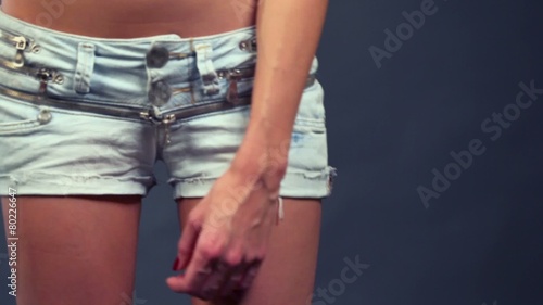 Haunches and hands of young woman poses in denim shorts photo