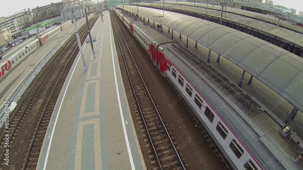 People walk near passengers train which stands at stations People walk near passengers train which stands at stations