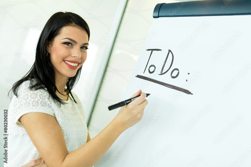Businesswoman writing ToDo onto a white writing board Businesswoman writing ToDo onto a white writing board