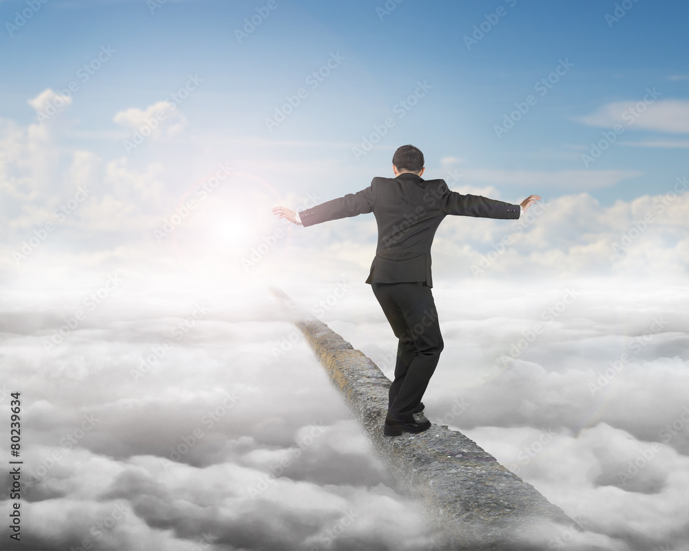 Businessman balancing on concrete ridge with sky sunlight clouds Businessman balancing on concrete ridge with sky sunlight clouds