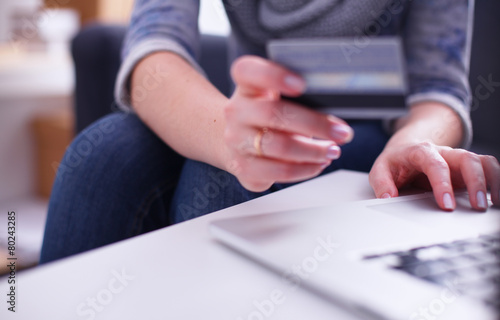 Woman sitting at the desk, shopping with laptop and credit card
