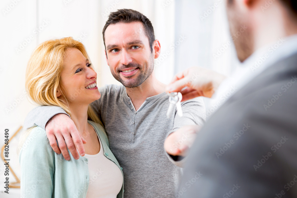 Real estate agent delivers keys of new house to young couple Real estate agent delivers keys of new house to young couple