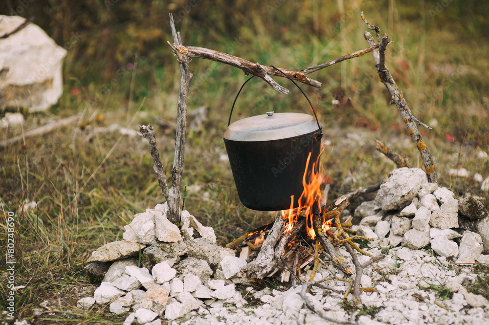 The image of a fire in the woods on which is brewed pot The image of a fire in the woods on which is brewed pot