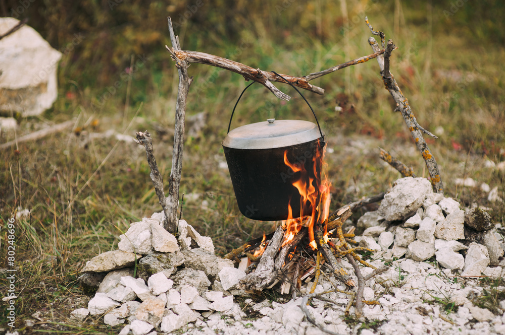 The image of a fire in the woods on which is brewed pot The image of a fire in the woods on which is brewed pot