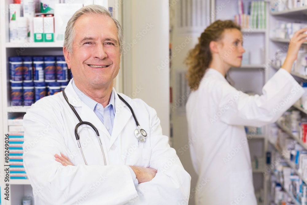 Pharmacist looking at camera with student behind him Pharmacist looking at camera with student behind him