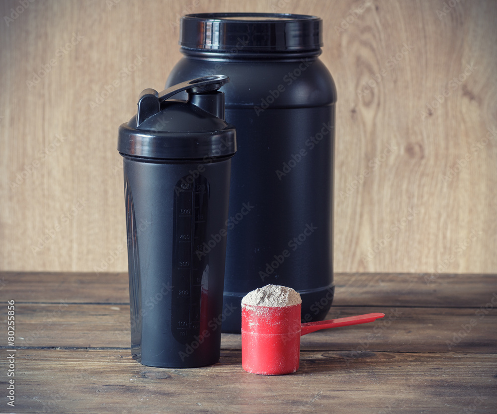 Whey protein powder in scoop and plastic shaker Whey protein powder in scoop and plastic shaker