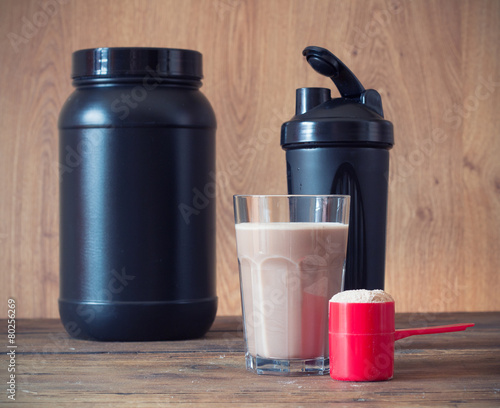 Whey protein powder in scoop and plastic shaker