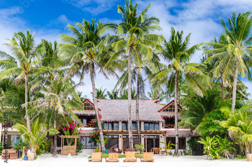 Luxury villa and palm trees at beautiful white sandy beach