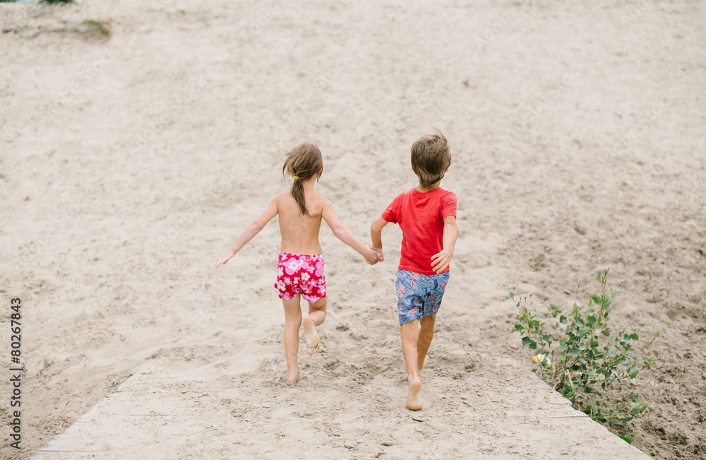 Fraternal twins run barefoot holding hands Fraternal twins run barefoot holding hands
