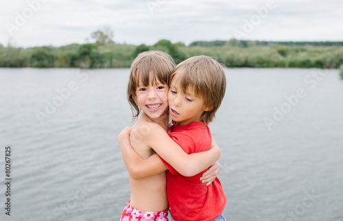 Fraternal twins hugging at the beach