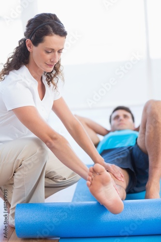 Trainer working with man on exercise mat