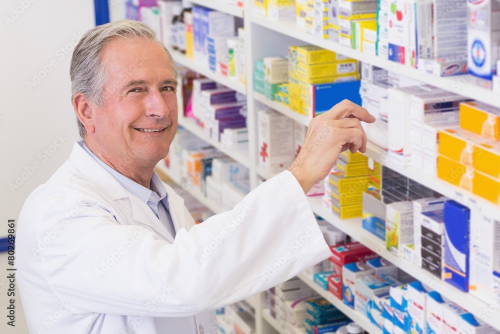 Senior pharmacist taking medicine from shelf