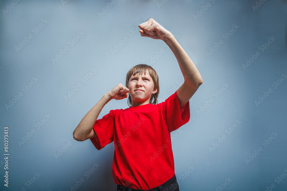 Boy, teenager, twelve years in a red shirt, showing his fists Boy, teenager, twelve years in a red shirt, showing his fists