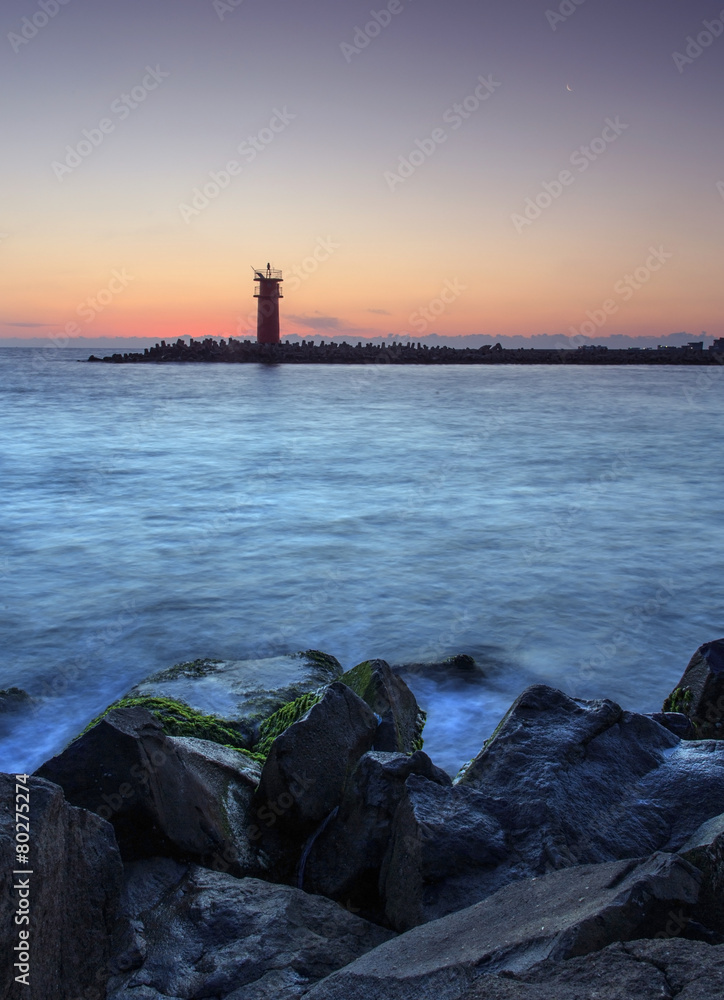 Beautiful nightly seascape with lighthouse and moody sky at the
