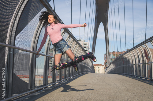 Beautiful young brunette jumping on a bridge