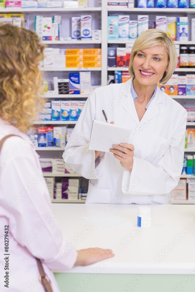 Pharmacist writing prescription in front of a customer