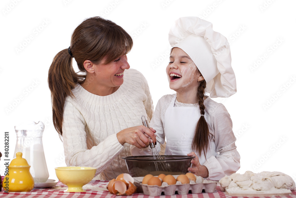 Happy mother with little daughter joyful cooking