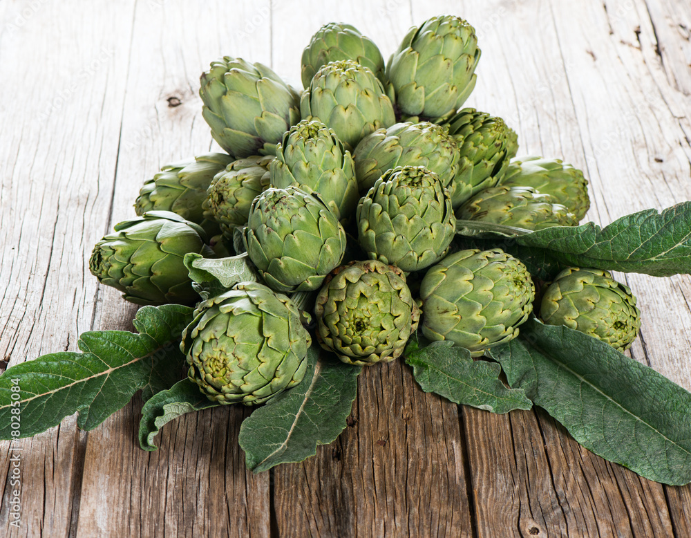 Natural artichokes over dark wooden table Natural artichokes over dark wooden table