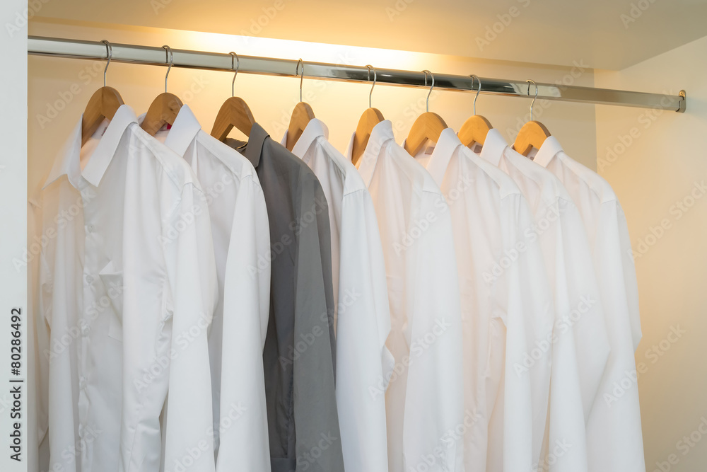 row of white and grey shirts hanging on coat hanger in white war