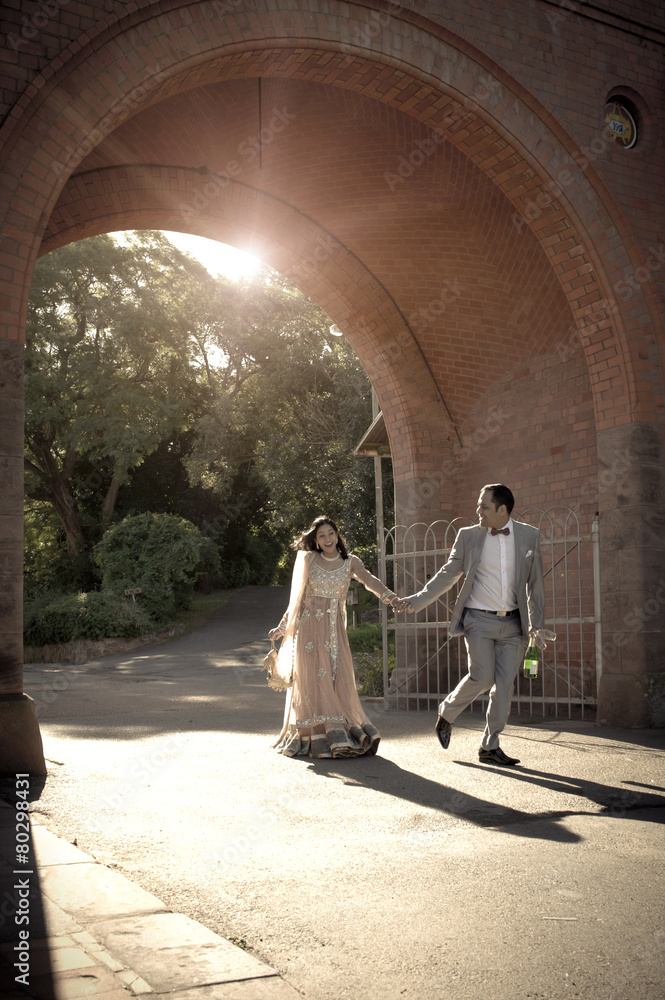 Young happy Indian couple walking outdoors under archway