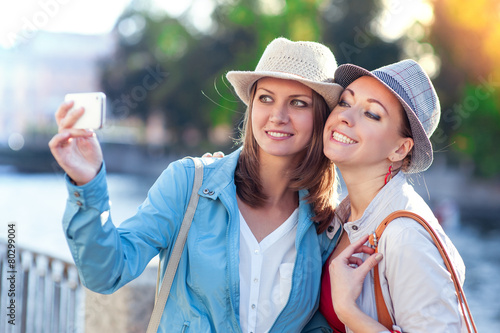 Two happy beautiful girls taken picture of themself in the city