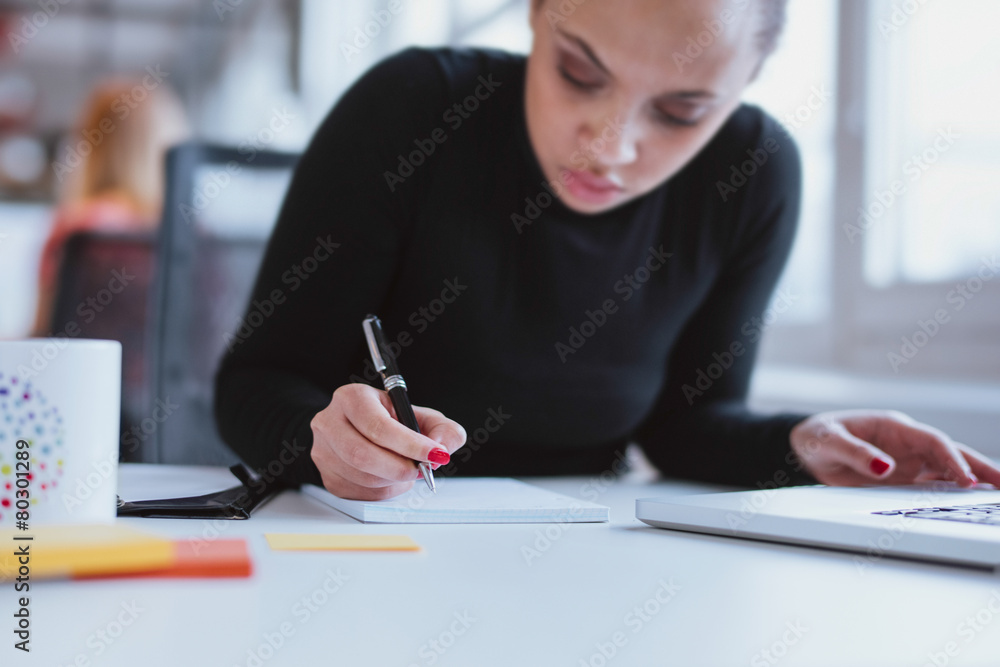 Young woman at her desk taking note Young woman at her desk taking note