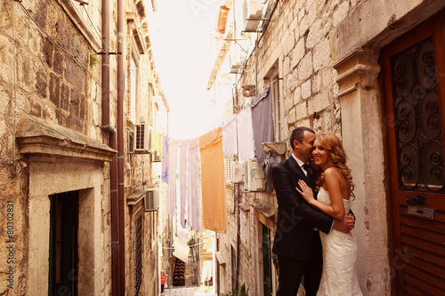 groom and bride on a narrow street © hreniuca