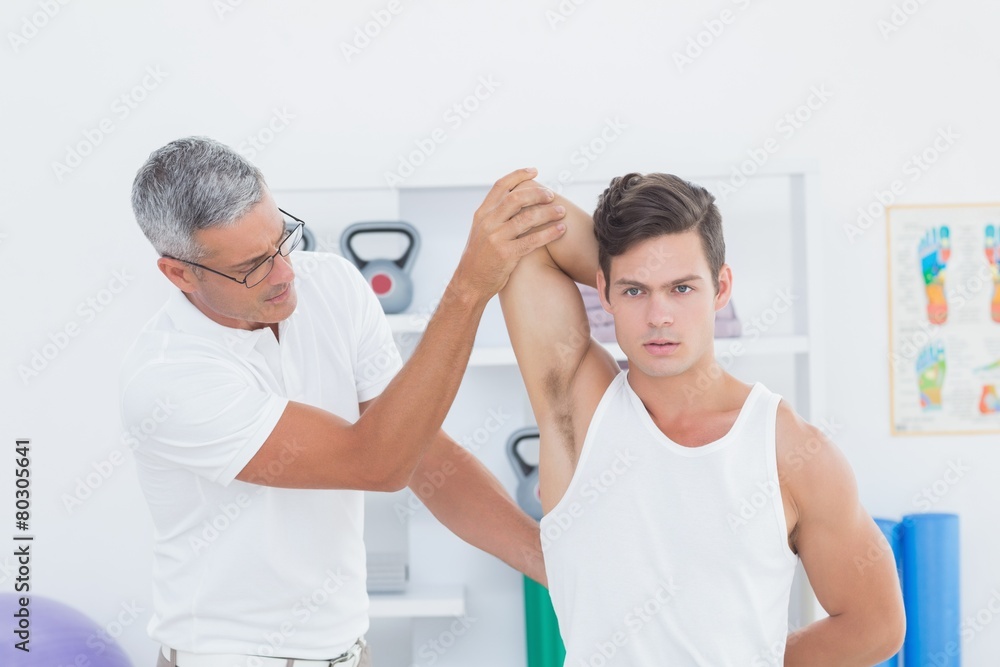 Doctor stretching a young man arm Doctor stretching a young man arm