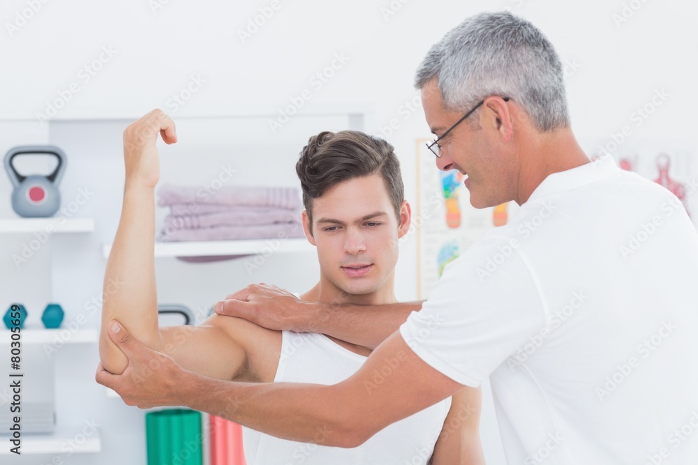 Fototapeta premium Doctor stretching a young man arm