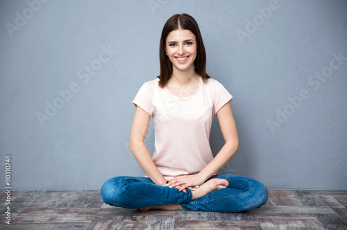 Happy young woman sitting on the floor with crossed legs