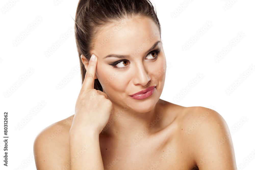 portrait of a beautiful young woman with the finger on forehead portrait of a beautiful young woman with the finger on forehead