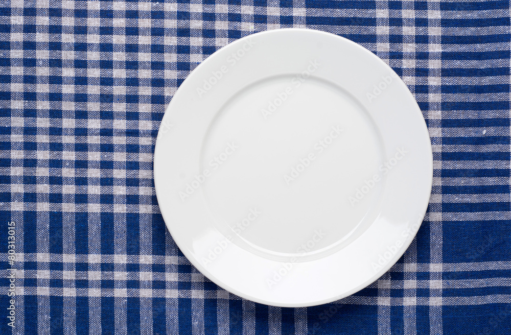 White classic plate on blue checkered tablecloth. White classic plate on blue checkered tablecloth.