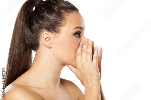 young woman whispering with her hands near the mouth