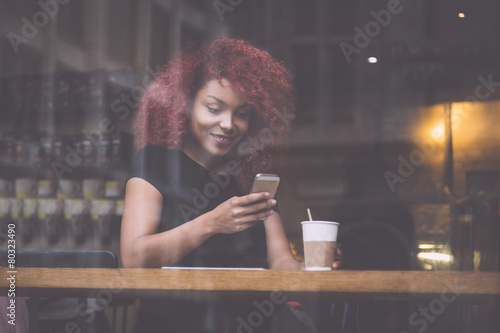 Beautiful girl in a cafe typing on smart phone photo