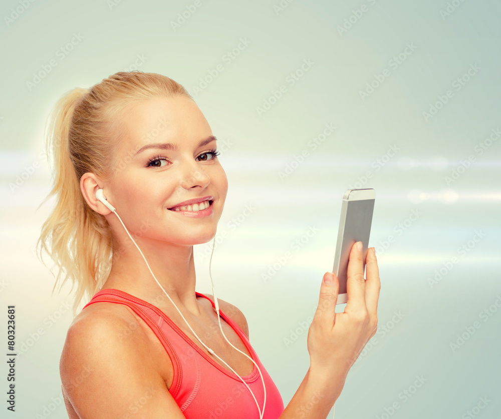 smiling sporty woman with smartphone and earphones