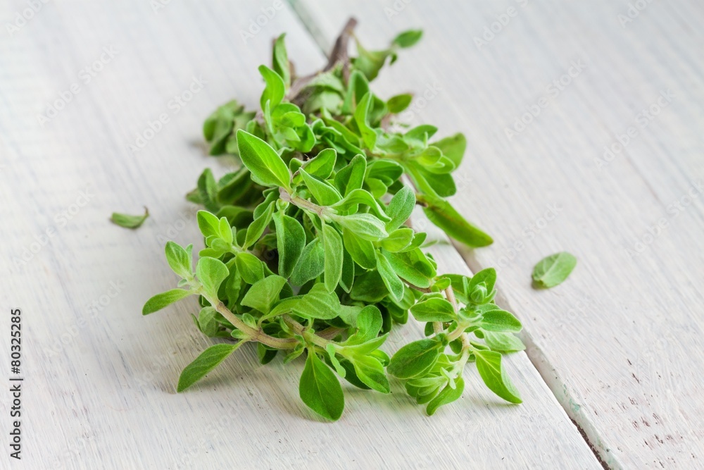 Green marjoram herb leaves on a wooden table Green marjoram herb leaves on a wooden table