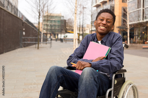 Fotobehang happy young disabled man in a wheelchair holding folders.