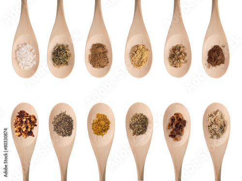 Various spices on wooden spoons isolated on white