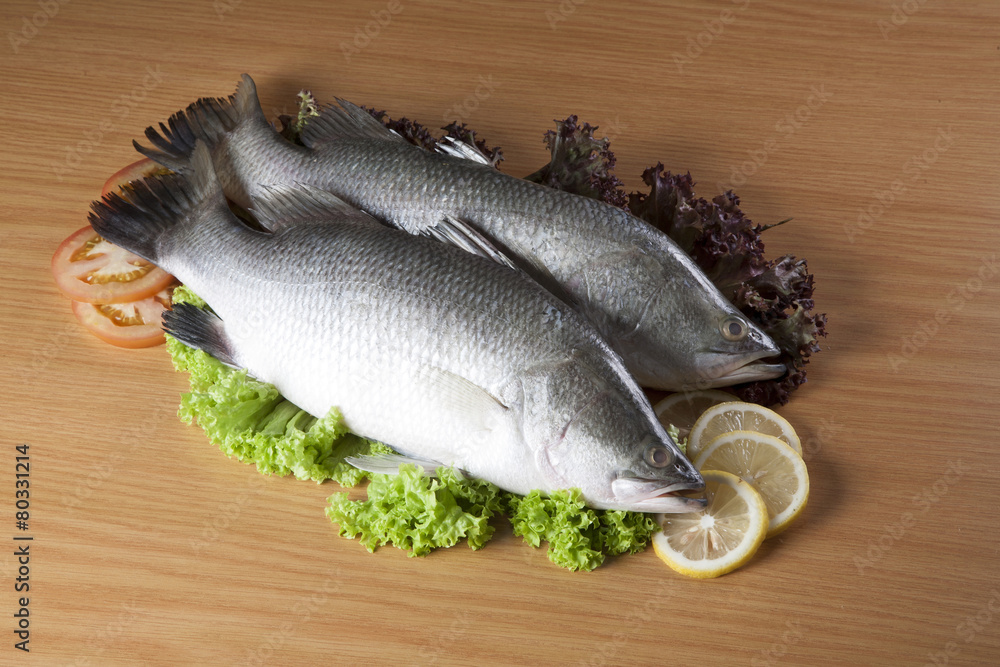 Fresh fish surrounded by lettuce ,lemon and tomatoo Fresh fish surrounded by lettuce ,lemon and tomatoo