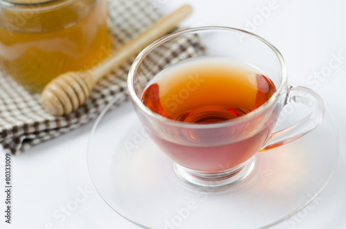 a cup of tea with honey on white background