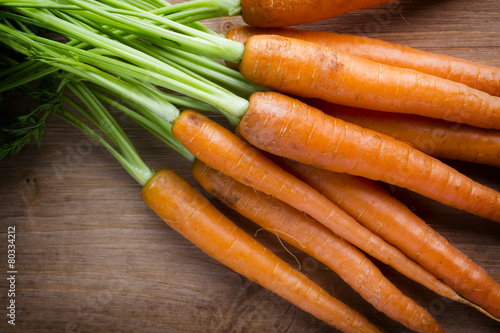 Fresh carrots on the wooden background.