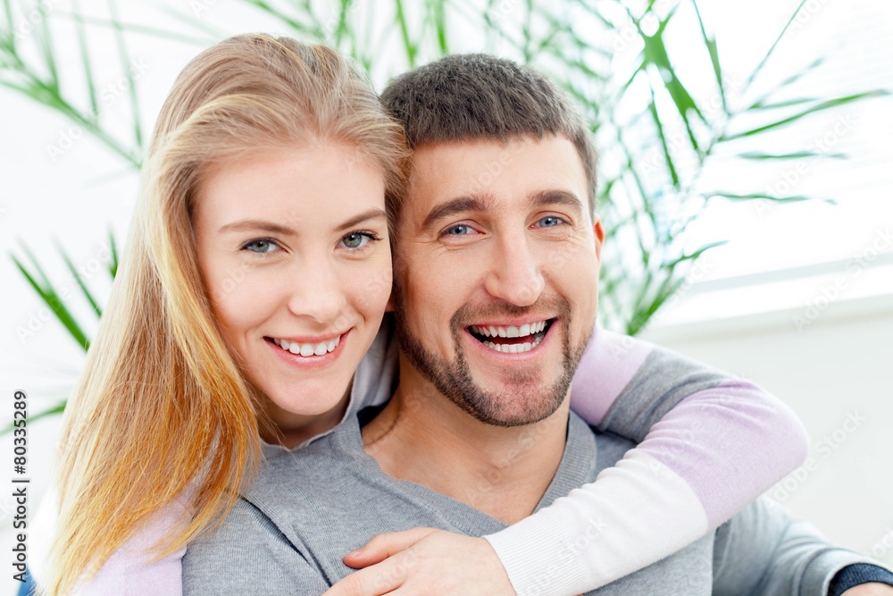 Fototapeta premium 50s. Smiling woman hugging her husband on the couch from behind