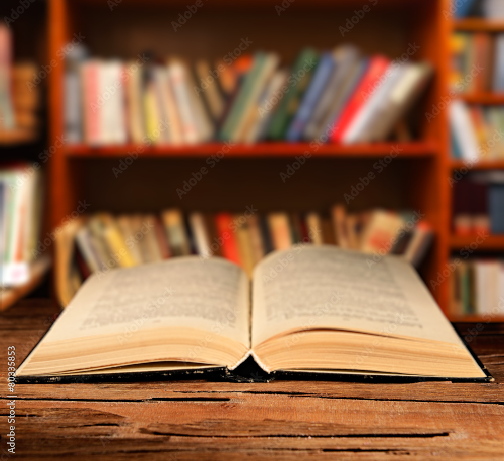 Open book on table on bookshelves background Open book on table on bookshelves background