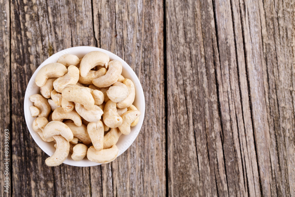 Fototapeta premium Cashew nuts on a plate on wooden background.