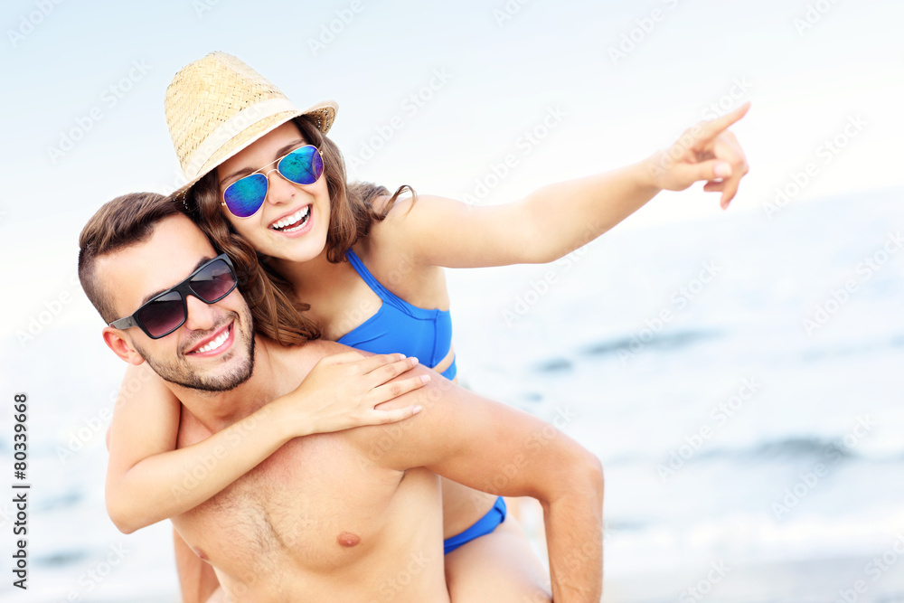 Young couple pointing at something at the beach Young couple pointing at something at the beach