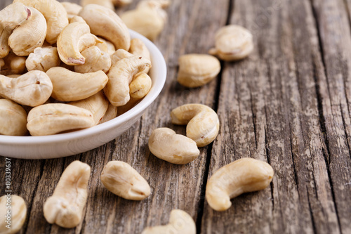 Cashew nuts on a plate on wooden background.