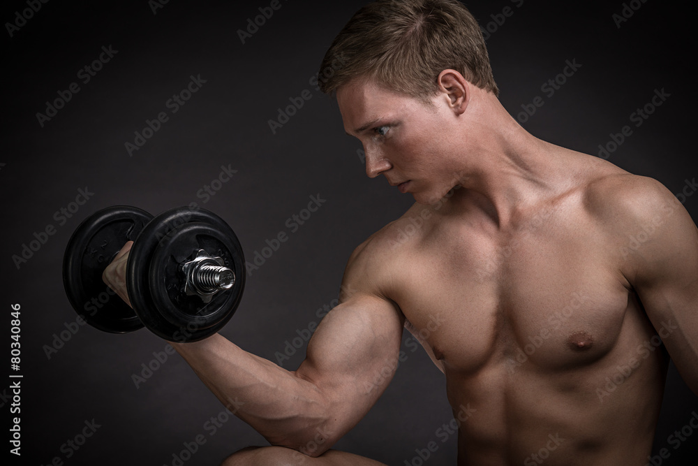 Muscular young man doing exercise with dumbbells