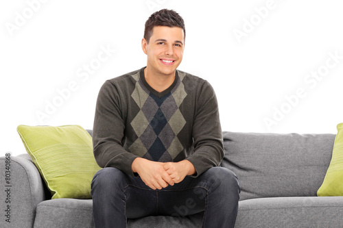 Cheerful handsome young man sitting on a modern sofa © Ljupco Smokovski