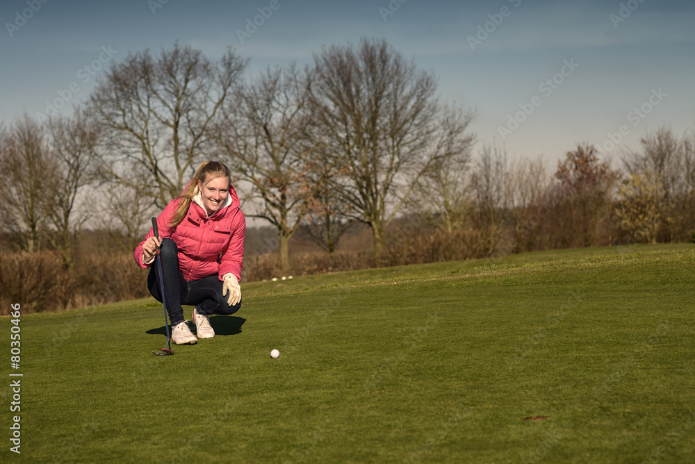 Weiblicher Golfer liest eine Puttlinie auf dem Grün