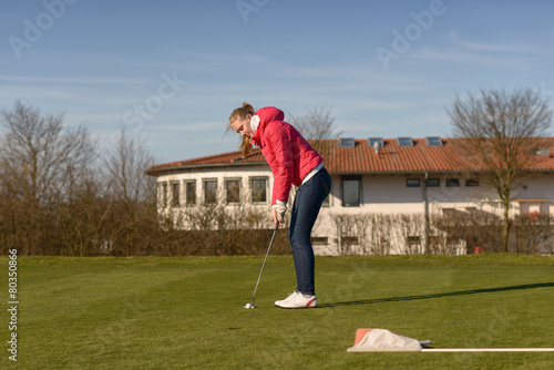 Junge Golferin spielt einen Putt auf dem Grün zum Loch